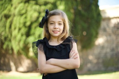 Yüzünde olumlu bir ifade olan güzel bir kızın belden yukarı portresi, kollarını kavuşturmuş, mutlu ve kendinden emin, gündelik kıyafetler giymiş.