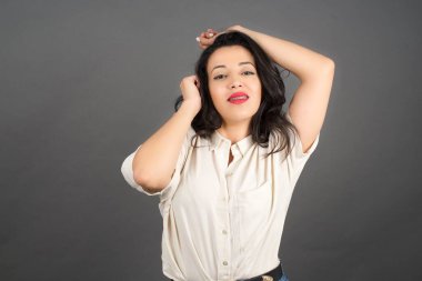 Güzel esmer kadın poz veriyor. Gri arkaplanda duruyor. 