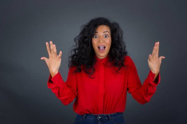 Kıvırcık saçlı, kırmızı gömlekli neşeli esmer kadın tezahürat yapıyor, başarıyı kutluyor, yumruklarını sıkarak evet diye bağırıyor.