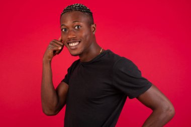 Çekici Afro-Amerikalı sıradan giyinmiş genç bir adam telefon konuşmasını taklit ediyor, cep telefonu tutar gibi elini kulağına yaklaştırıyor, kendine güvenen bir yüz ifadesi var, dışarıda izole edilmiş. Ara beni.!