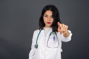 Neşeli genç doktor kadının kapalı çekimleri sizi mutlu eder, rekabeti seçer, olumlu bir ifadeye sahiptir, tercihini yapar, gri duvarda izole edilmiş bir şekilde..