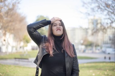 Parkta eli başının üstünde genç ve güzel bir kadın.