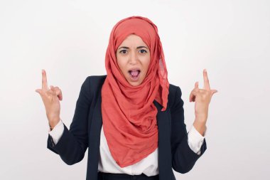 Bu dünyayı sallamak için doğmuşum. Neşeli Müslüman kadın siyah spor ceket giyer ve tesettürlü bağırır ve kollarını kaldırmış kornalarla ya da rock hareketleriyle gösterir. Konserde olmanın heyecanını ifade eder..