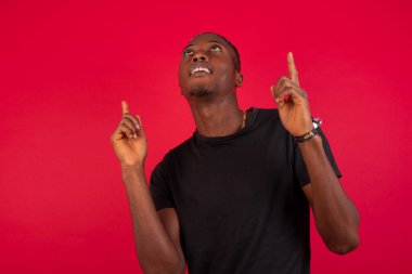 Başarılı, dost canlısı, Afro-Amerikalı genç bir adamın işaret parmağıyla işaret ederek boş bir fotokopi duvarında şok edici bir şey gösterdiği yatay görüntüsü..