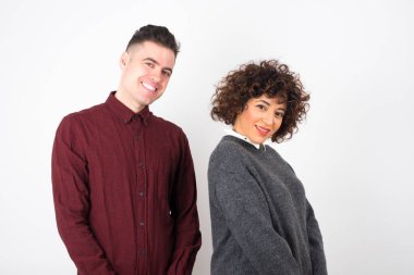  Gri stüdyo arka planına zımparalanmış günlük kıyafetler giyen çift utangaç hissediyor..