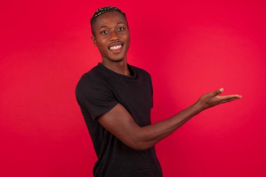 Kırmızı arkaplan üzerine siyah tişört giyen Afro-Amerikan bir adam, 