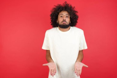 Afro saçlı genç adamın kırmızı duvara karşı kafası karışık.   