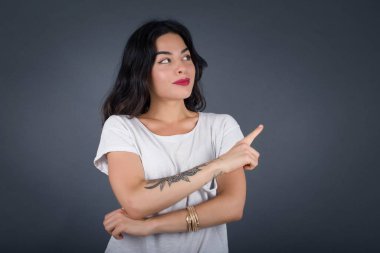 Kamerada poz veren güzel esmer bir kadın. Alengirli bir bakışla ve el kol hareketleriyle. Bayan tasarımcı, işaret parmağıyla harika bir ürün sunuyor. Hareket kavramı.