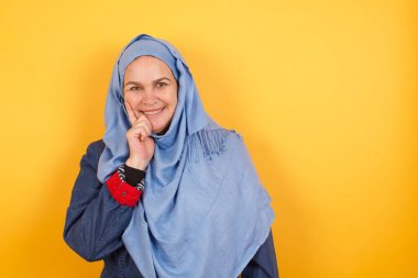 Kaygısız, orta yaşlı, tesettürlü, kendinden emin, dokunaklı, dik dik bakan, başını eğen beyaz dişli Müslüman kadın.