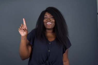 Hoş görünümlü Afro-Amerikan bir kadının yakın portresi akıllı bir ifadeye sahiptir, bir parmağını kaldırır, önemli bir şeyi söylemeyi unutmaması gerektiğini hatırlar. Kapalı