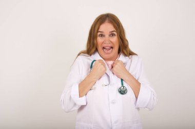 İnsan yüzü ifadeleri ve duyguları. Kafkasyalı yetişkin kadın doktor portresi paniğe kapılmış görünüyor, ellerini yüzüne yakın tutuyor, ağzı sonuna kadar açık. Sürpriz ve şok..