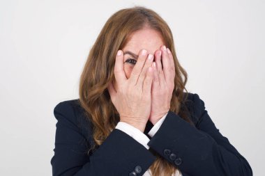 Endişe. Orta yaşlı güzel bir kadının kavramsal bir görüntüsü. Ellerini yüzünü kapatıyor ve parmaklarının arasından dışarı bakıyor. Bir şeyden ya da birinden korktun mu?.