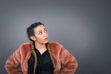 Neşeli mavi gözlü kızın belinden yukarı bakıp bir şey düşündüğü. Ellerini kalçaya koy, yüz ifadenden şüphe et. Gri duvara yaslanmış bir şey olup olmadığını merak ediyorum..