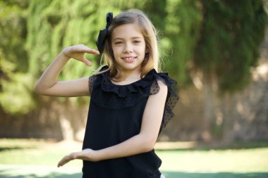 Sarışın Avrupalı bir kız, elleri büyük ve büyük bir işaret, ölçü sembolü gösteriyor. Kameraya bakıp gülümsüyor. Ölçüm konsepti.