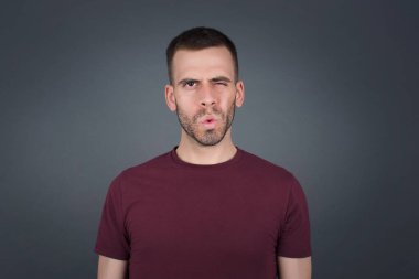 Gayri resmi giyinmiş esmer bir adam tiksinti, isteksizlik, hoşnutsuzluk ve umursamazlık ifadesi sergiliyor. Keyifli görünümlü bir Cauasian adam. Sinir bozucu bir şeye benziyor.