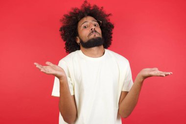 Afro saçlı genç adamın kırmızı duvara karşı kafası karışık. 