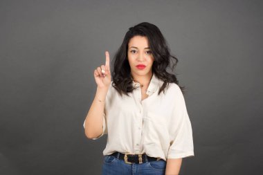 Gayri resmi giyinmiş güzel esmer kadın. Gri arkaplanda duruyor. 