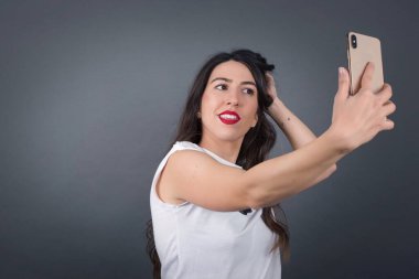 Gri arka planda selfie çeken güzel bir kadın..  