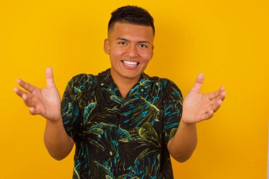 Soyutlanmış arka planda rahat kıyafetler giyen yakışıklı İspanyol adam sarılmak için kollarını açmış kameraya bakıyor. Mutluluğu kucaklayan neşeli bir ifade..