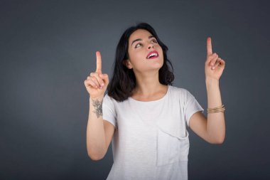 Başarılı, dost canlısı, parlak makyajlı, parlak saçlı bir kadının işaret parmağıyla işaret ederek boş bir fotokopi duvarında şok edici bir şey gösterdiği yatay bir görüntü..