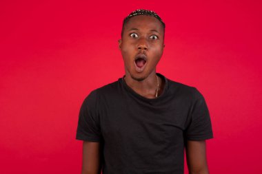 Etkileyici yüz ifadeleri. Şok olmuş afro-amerikan bir adam çenesini kapalı tutuyor boş duvarda gördüklerinden sersemlemiş hissediyor