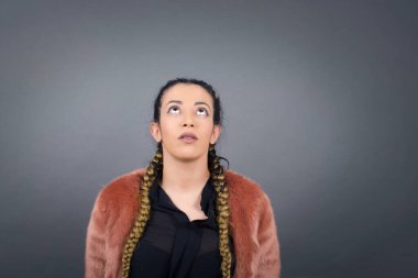 Gizemli büyüleyici kadının portresi gri duvara gizemli bir gülümsemeyle bakıyor..