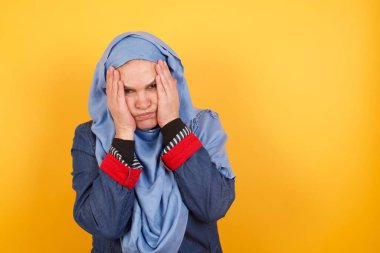 Orta yaşlı, tesettürlü Müslüman bir kadının portresi. Mutsuz bir ifadeyle el ele tutuşmuş, hayvanlar hakkında hüzünlü bir film izliyor ve ağlamamaya çalışıyor..