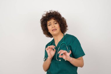 Ne kadar iğrenç! Tıbbi üniforma giyen güzel Arap doktor kadın, arka planda iğrenç ya da iğrenç bir şey gördüğü için tatminsiz bir yüz ifadesi takındı..