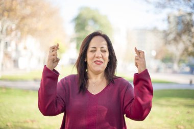 Parkta parmakları çapraz olan orta yaşlı güzel bir Arap kadın.  