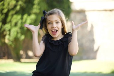 Başarı, başarı konsepti. Siyah elbiseli neşeli şirin kız ellerini kaldırıyor, mutluluk dolu gözleri büyük başarılarını kutluyor. Resmi olarak giyinmiş çekici beyaz kadın..