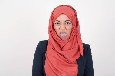 Vücut dili. İğrençti. Güzel Müslüman kadın gri duvara karşı siyah ceket ve tesettür giyiyordu. Suratı asıktı..