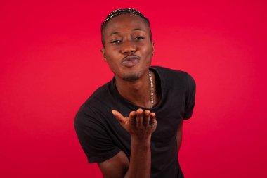 Sevimli Afro-Amerikan erkeği kameraya öpücük yolluyor, kız arkadaşına sevgisini gösteriyor ya da uzaktan veda ediyor, stüdyo arka planında izole edilmiş. Çekici genç adam birine sempati gösterir..