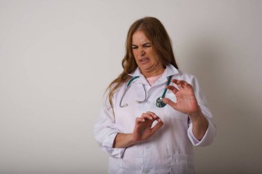 Ne kadar iğrenç! Memnun olmayan genç doktor kadın, arka planda iğrenç ya da tiksindirici bir şey gördüğü için yüz ifadesinden memnun değil..