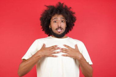 Afro saçlı genç adamın kırmızı duvara karşı kafası karışık.   