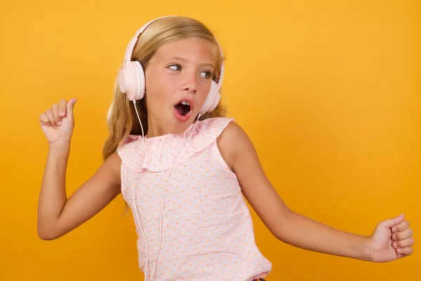 Schattig Klein Meisje Roze Jurk Tegen Gele Studio Achtergrond Hoofdtelefoon — Stockfoto