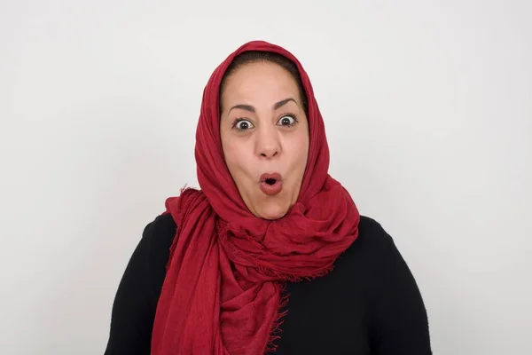 Headshot of goofy surprised bug-eyed young woman student wearing casual grey t-shirt staring at camera with shocked look, expressing astonishment and shock, screaming Omg or Wow