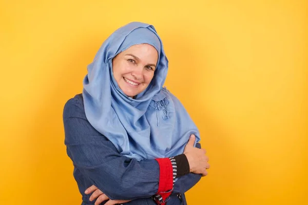 Shy girl smiling looking to the camera. Caucasian charming girl sanding against gray studio background feeling shy.