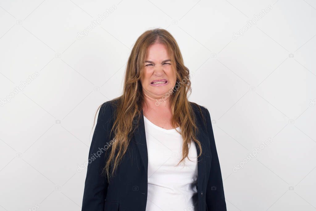 Negative human expressions and attitude. Angry dissatisfied middle aged female has disgusting expression as sees something not appealing, frowns face, isolated over white  background. Distaste and dislike