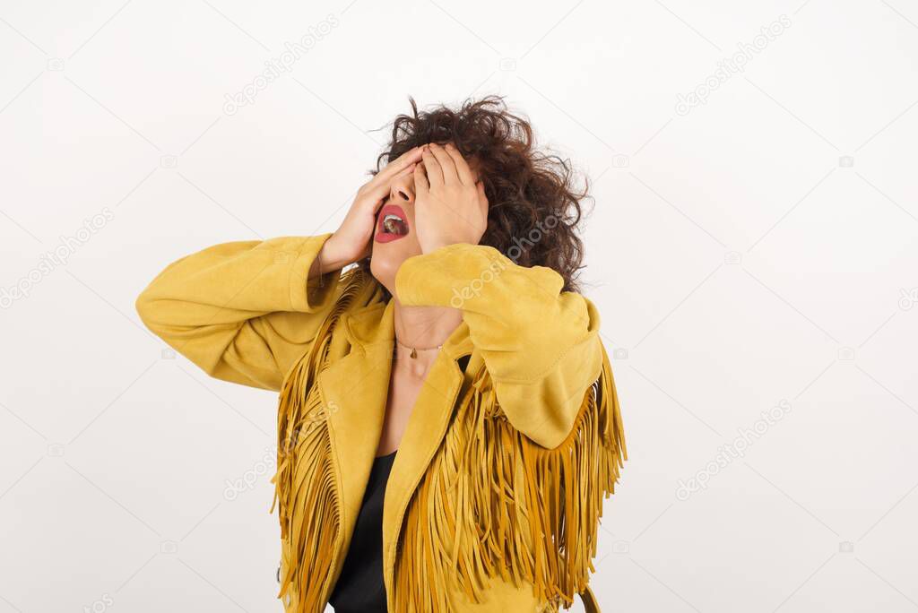 Shocked panic girl dressed in stylish clothing holding hands on face covering eyes and screaming in despair and frustration while being full of terror, mouth dropped open.