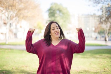 Parkta elleri havada, orta yaşlı, güzel bir Arap kadın.  