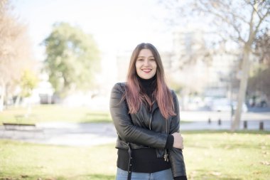 Genç ve güzel bir kadın parktaki kameraya bakıyor. 