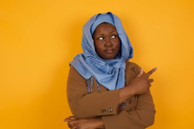 Heyecanlı, modaya uygun Afrikalı Amerikalı Müslüman kadın moda reklamcılığı bilgisi veya promosyon metinleri için sarı arka plan fotokopisini mutlulukla kenara çekti..