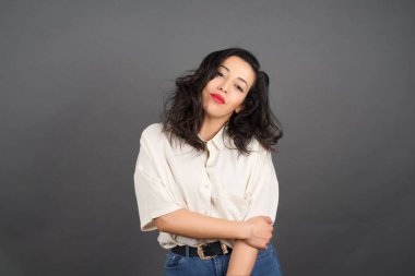 Gri arka planda gelişigüzel giyinmiş güzel esmer kadın..  