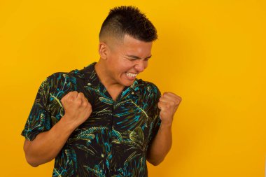 İspanyol adam başarısını ve zaferini sevinçle kutluyor ve yumruklarını zevkle sıkıyor. Hedeflerine ve hedeflerine ulaşmaktan mutlu olan şanslı adam. Olumlu duygular, duygular.