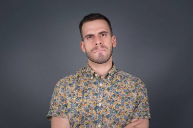 Düşüncelere dalan, kaşlarını kaldıran, dudaklarını kıvıran, şık kıyafetler giyen, metnin için fotokopi alanı olan gri duvara karşı duran düşünceli çekici bir adam..