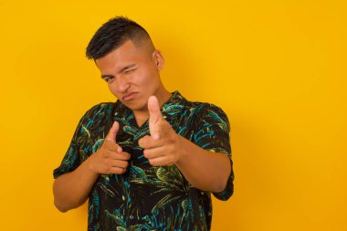 Hey sen, bang. Neşeli ve karizmatik yakışıklı İspanyol adam beyaz duvarın üzerinde mutlu ve küstahça poz veriyor ve parmaklarıyla kamerayı işaret ediyor.