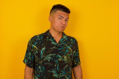 Züppe ifadeli güzel İspanyol bir adam dudaklarını kıvırıyor ve kaşlarını kaldırıyor şüpheli ve şüpheci bir ifadeyle şüpheli ve şüpheci bir ifadeyle bakıyor. Arka planda kapalı duruyor..