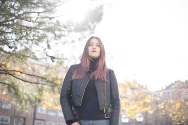 Genç ve güzel bir kadın parktaki kameraya bakıyor.  