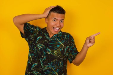 Şok olmuş yüz ifadesi olan genç İspanyol bir adamın portresi, boş alanda şaşırtıcı bir şey gösteriyor, bir eli kafasında ve işaret parmağıyla işaret ediyor. OMG kavramı.