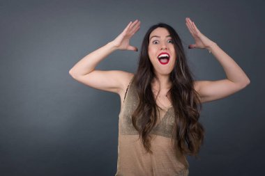 Güzel bir kadının kafası karışıktır. Gri arkaplanda duruyor. 